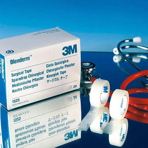 blenderm hypoallergenes fixierpflaster welches auf blauen Hintergrund neben einem roten Stetoskop und zwei Einzelexemplaren des Produkts in Originalverpackung steht.jpg